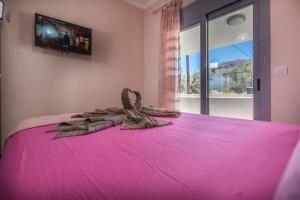a bedroom with a pink bed with a tv on the wall at Extreme House in Archangelos