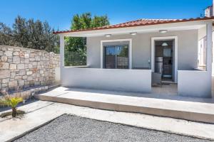 a small white house with a stone wall at Extreme House in Archangelos