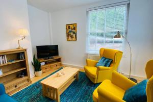 a living room with a yellow couch and a tv at Historic Kelham House with FREE on-site Parking in Sheffield