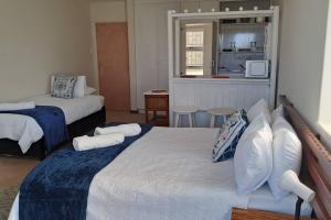 une chambre d'hôtel avec deux lits et une cuisine dans l'établissement Ryans Surf Cabin, à Jeffreys Bay