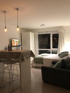 1 dormitorio con cama, mesa y sofá en BettyStudio, cálido, centrico c/ vista a los Cerros en San Carlos de Bariloche