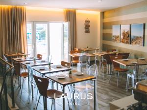 a dining room with tables and chairs and windows at Laurus Hotel in Lourinhã