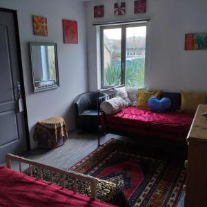 een woonkamer met een rode bank en een raam bij The Annex in Saint-Maur-des-Bois