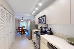 a kitchen with white cabinets and a dining room at Sea-Renity, Unit H-205 in Naples