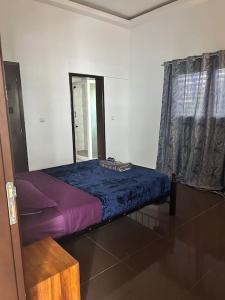 a small bed in a room with a window at Cozy Apartment in Cotonou