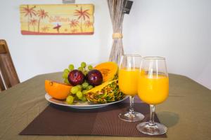 zwei Gläser Orangensaft und einen Obstteller in der Unterkunft Charming flat with AC and balcony - Le Moule - Welkeys in Le Moule