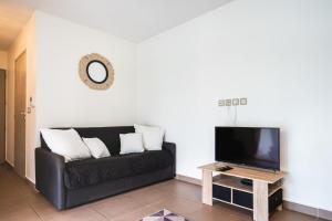 ein Wohnzimmer mit einem schwarzen Sofa und einem TV in der Unterkunft Charming flat with AC and balcony - Le Moule - Welkeys in Le Moule