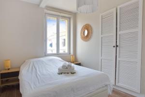een witte slaapkamer met een bed en een raam bij Very nice flat with AC two steps away from the sea - Bandol - Welkeys in Bandol