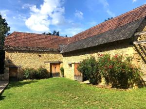 ein altes Steingebäude mit rotem Dach in der Unterkunft Les Gîtes du Fraysse, au paradis des oiseaux in Montignac