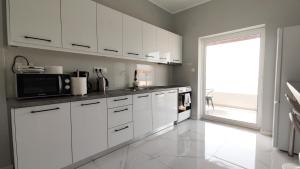 a kitchen with white cabinets and a large window at Villetta del mare corfu in Perivolion +17 photos