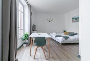 Habitación blanca con cama, escritorio y mesa. en Résidence Bains Callou située face aux thermes en Vichy