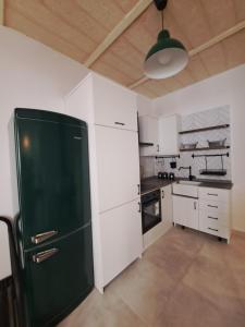 a kitchen with a green refrigerator and white cabinets at Ta' Wenzu in Birgu