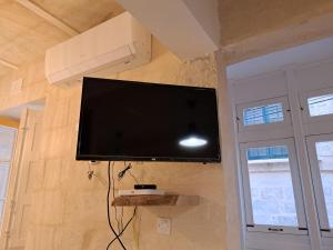 TV de pantalla plana colgada en la pared en Ta' Wenzu, en Birgu