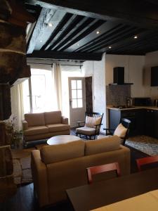 a living room with couches and tables and a kitchen at Gîte de la Tournelle in Pradelles