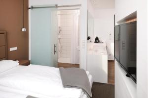a bedroom with a white bed and a bathroom at Hotel INNdependence in Mainz