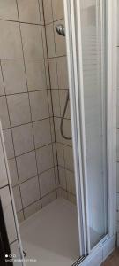 La salle de bains est pourvue d'une douche avec une porte en verre. dans l'établissement Hotelik Kościerzyna, à Kościerzyna