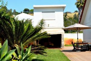 Casa con patio con mesa y sombrilla en Lisbon Surf + Beach Villa, en Costa da Caparica