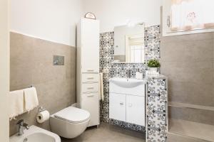 ein Bad mit einem WC, einem Waschbecken und einem Spiegel in der Unterkunft Liberty Suite Regina Elena in Avola