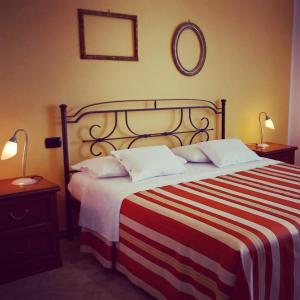 a bedroom with a bed with a striped blanket and two lamps at Cascina Longoria in Neive