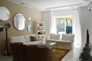 a living room with white furniture and a mirror at Lisbon Surf + Beach Villa in Costa da Caparica