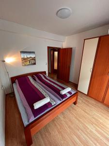 a bedroom with a large bed with purple sheets at Korun's Lakeview Apartment in Lagadin