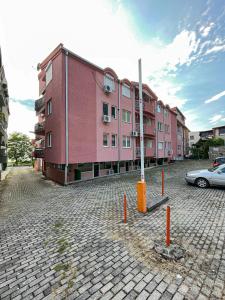 różowy budynek z samochodem zaparkowanym przed nim w obiekcie Korun's Lakeview Apartment w mieście Łagadin