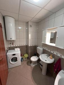 uma pequena casa de banho com uma máquina de lavar roupa e um lavatório em Korun's Lakeview Apartment em Lagadin