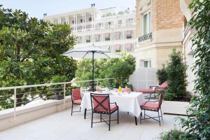 un patio avec une table, des chaises et un parasol dans l'établissement Le Bristol Paris, Oetker Hotels, à Paris