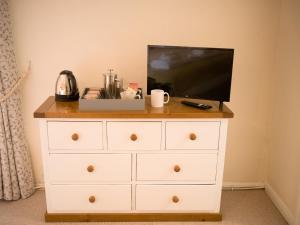 a white dresser with a television on top of it at The Old Thatch Inn in Cheriton Bishop