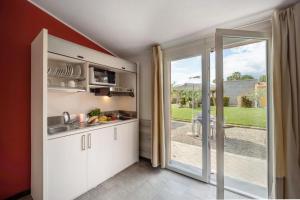 a kitchen with white cabinets and a sliding glass door at ReBi Village in Imperia