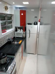 a kitchen with a white refrigerator and a stove at Apartamento Lindíssimo e Moderno próximo a praia in Praia Grande