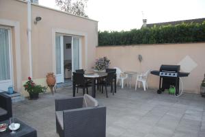 a patio with a table and chairs and a grill at Logement agréable et tranquille in Fontenay-Trésigny