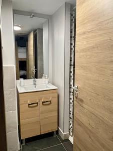 baño con lavabo, espejo y puerta en Studio neuf et chaleureux, en Vars