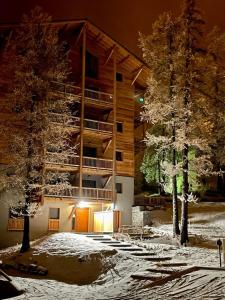 瓦爾的住宿－Studio neuf et chaleureux，雪中一座建筑,前面有树木