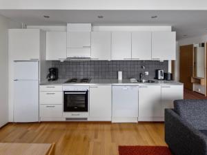 a white kitchen with white appliances and a couch at Holiday Home Nordic chalet 9312 by Interhome in Ylläsjärvi