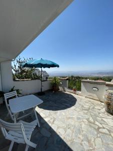 una mesa y sillas en un patio con sombrilla en Acogedor apartamento con fantásticas vistas., en La Zubia