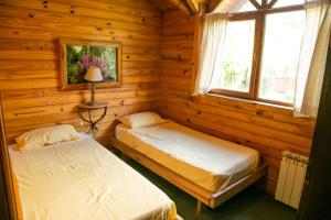 a bedroom with two beds in a log cabin at Cabañas Dulce Sofía in San Carlos de Bariloche