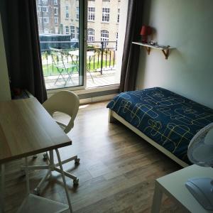 Schlafzimmer mit einem Bett, einem Tisch und einem Fenster in der Unterkunft Résidence Zola in Le Havre