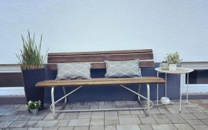 a wooden bench with two pillows and a side table at Ferienwohnung am Park in Schwabmünchen in Schwabmünchen