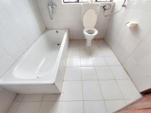 a white bathroom with a tub and a toilet at Hill View Garden Hotel in Moshi