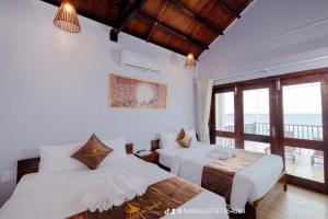 a bedroom with two beds and a balcony at The Poplar Resort Phú Quốc in Phu Quoc