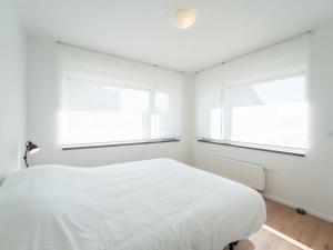 um quarto branco com 2 janelas e uma cama em Apartment Caddy by Interhome em De Haan