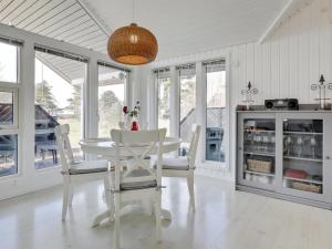 uma sala de jantar branca com uma mesa e cadeiras brancas em Holiday Home Greta - 200m from the sea in Bornholm by Interhome em Vester Sømarken
