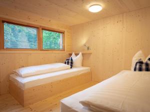 2 Betten in einem Holzzimmer mit 2 Fenstern in der Unterkunft Apartment Glamping Lodge A by Interhome in Ossiach