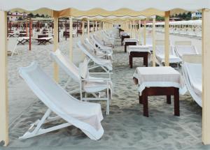 a row of chairs and tables on a beach at Hotel La Pigna in Marina di Pietrasanta
