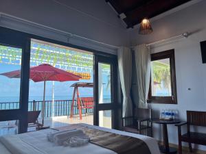 a bedroom with a bed and a balcony with an umbrella at The Poplar Resort Phú Quốc in Phu Quoc