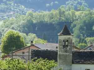 un edificio con una torre dell'orologio di fronte a una montagna di Apartment Casa Lara by Interhome a Olivone