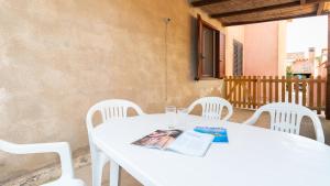 una mesa blanca con sillas blancas y una revista en ella en Sardinianworld - Sandy House, en Putzu Idu 37 fotos más
