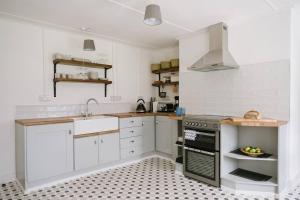 uma cozinha com armários brancos e um forno com placa de fogão em Eala House em Donegal