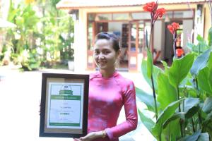 a woman is holding a sign in front of some plants at The Earth Villa in Hoi An